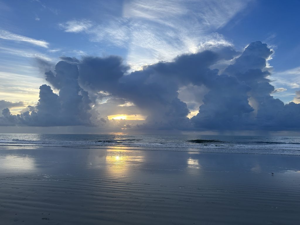 Sunrise over Cocoa Beach, Florida, with the sun appearing in a gap between two clouds. 